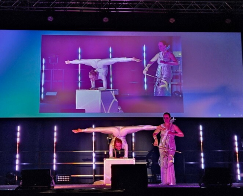 Kontorsionistin mit Cellistin bei Messe Event Kontorsionistin buchen für Firmenevent, Galadinner, Veranstaltung, Weihnachtsfeier